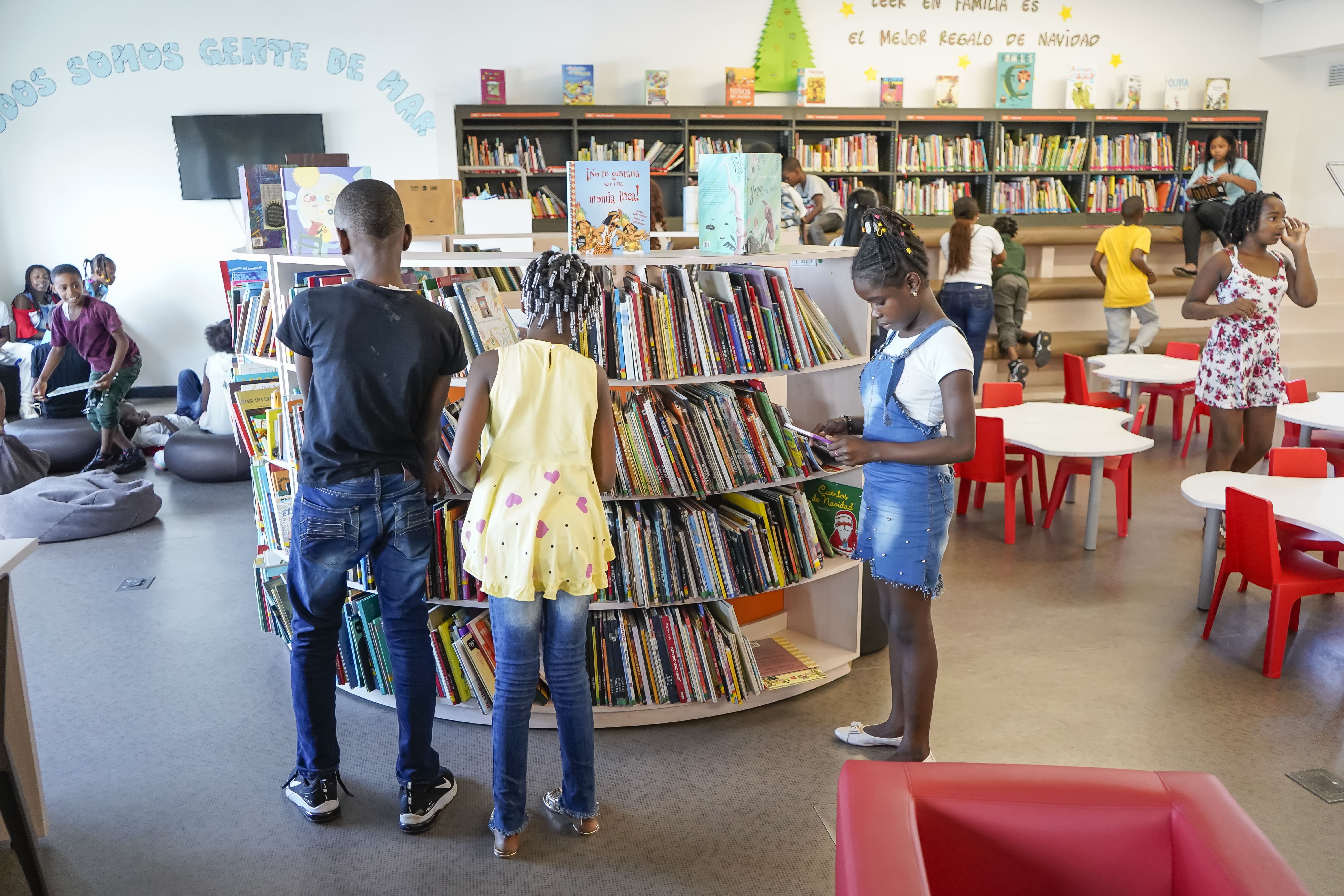la imagen puede contener niños que se encuentran en una biblioteca,algunos leyendo.